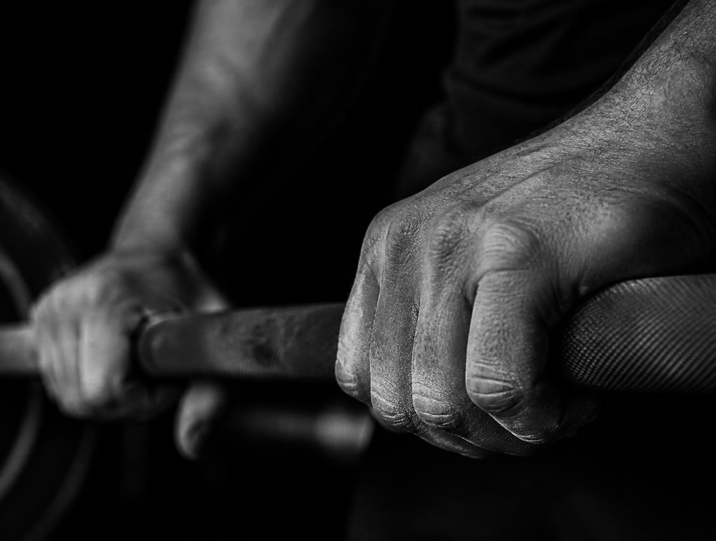 Chalked hands gripping a knurled barbell